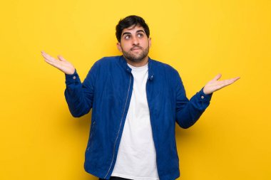 Adam sarı duvar yapım üzerinde mavi ceket ile jest şüphe ediyor.