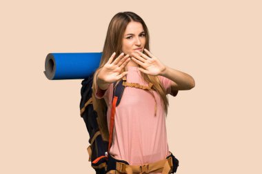 Sırt çantalı genç kadın biraz gergin ve korkmuş. Sarı arka planda ellerini öne uzatıyor.