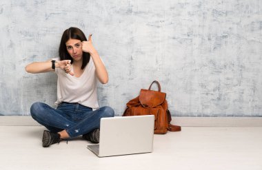 Yerde oturan öğrenci kadın iyi-kötü işareti yapıyor. Evet ya da değil arasında kararsız