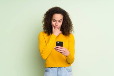 Izole yeşil arka plan düşünme ve bir mesaj gönderme üzerinde Dominikli kadın