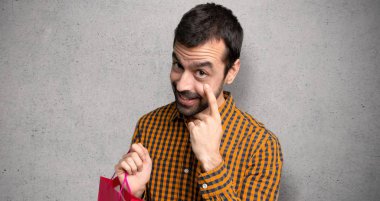 Dokulu duvar üzerinde ön bakarak alışveriş torbaları ile Adam