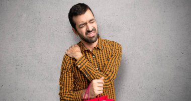 Dokulu duvar üzerinde bir çaba yapmış olması için omuz ağrısı çeken alışveriş çantaları ile Adam