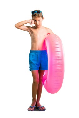 Yalıtılmış beyaz arka plan üzerinde olumsuz ifade ile başparmak aşağı işareti gösteren yaz tatilinde Çocuk tam uzunlukta bir çekim