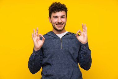 Parmakları ile ok işareti gösteren izole sarı duvar üzerinde genç adam