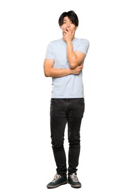 Izole beyaz arka plan üzerinde bakarken mavi gömlek li asyalı bir adamın tam uzunlukta bir çekim şaşırttı ve şok