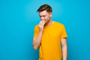 Mavi duvarın üzerinde kızıl saçlı adam çok gülümsüyor