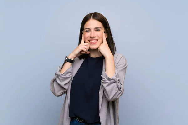 Young woman over isolated blue wall smiling with a happy and pleasant expression