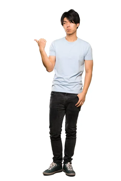 一个穿着蓝色衬衫的亚洲男子的全长镜头不快 指着一边孤立的白色背景 — 图库照片