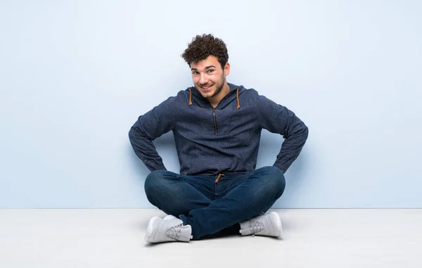 Jovem Sentado Chão Posando Com Braços Quadril Sorrindo — Fotografia de Stock