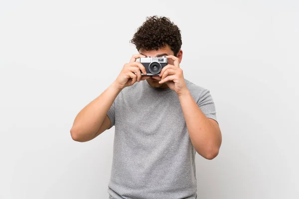 Muž Kudrnatými Vlasy Izolované Stěně Držící Fotoaparát — Stock fotografie