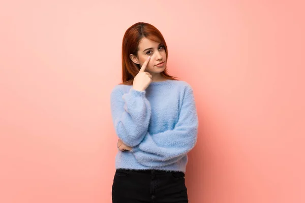 Young redhead woman over pink background looking to the front