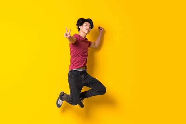 Asiático homem saltando sobre isolado amarelo parede — Fotografia de Stock