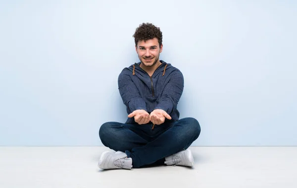 Young Man Sitting Floor Holding Copyspace Imaginary Palm Insert — Stock Photo, Image