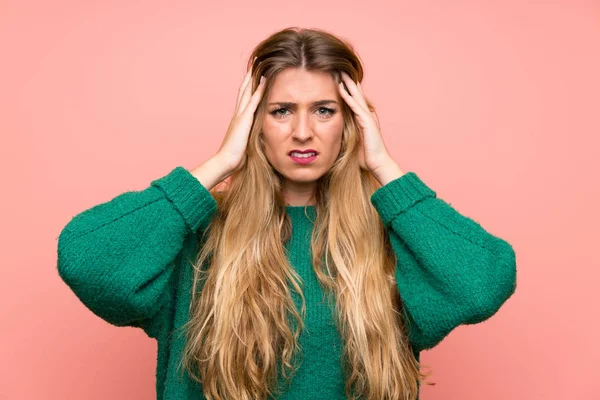 ピンクの壁の上に緑のセーターを着た若いブロンドの女性は不幸で何かに不満 否定的な表情 — ストック写真