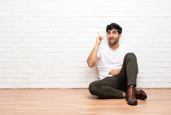 指を持ち上げながら解決策を実現しようとして床に座っている若い男 — ストック写真