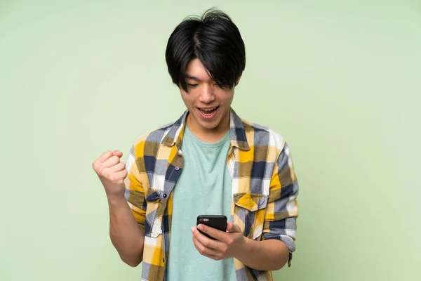 Asiático Hombre Sobre Aislado Verde Pared Usando Móvil Teléfono —  Fotos de Stock