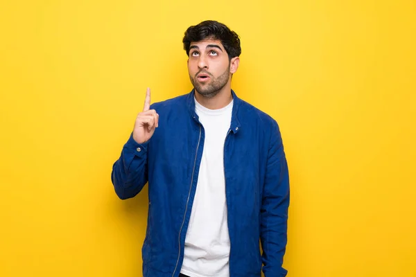 Mann Mit Blauer Jacke Über Gelber Wand Zeigt Nach Oben — Stockfoto