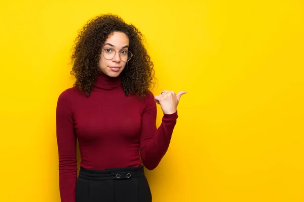 Dominican woman with turtleneck sweater pointing to the side to present a product