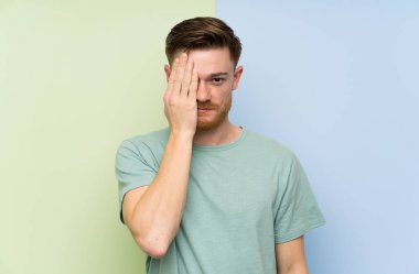 El ile bir göz kapsayan renkli arka plan üzerinde Redhead adam