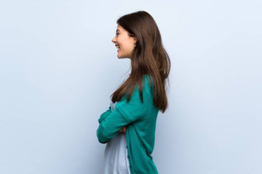 Genç kız lateral pozisyonda mavi duvarın üzerinden