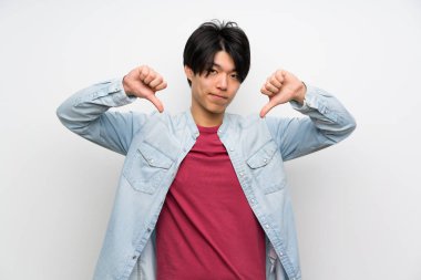 Izole beyaz arka plan üzerinde Asyalı adam başparmak aşağı gösteren