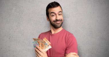 Dokulu duvar üzerinde mutlu ifade ile çok para alan adam