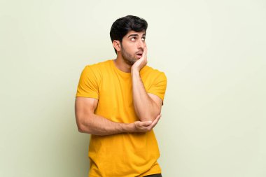 Pembe duvar üzerinde genç adam sürpriz ve doğru bakarken şok