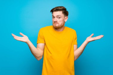 Mavi duvar üzerinde Redhead adam şüphe jest yapma