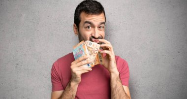 Dokulu duvarın üzerinde sessizlik jesti gösteren çok para alan adam