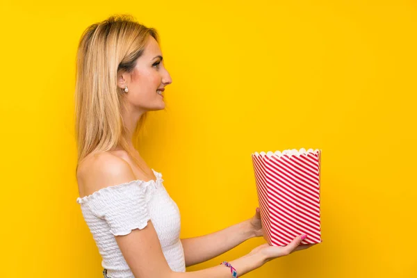 Mladá Blondýna Žena Přes Izolované Žluté Zdi Drží Misku Popcornů — Stock fotografie