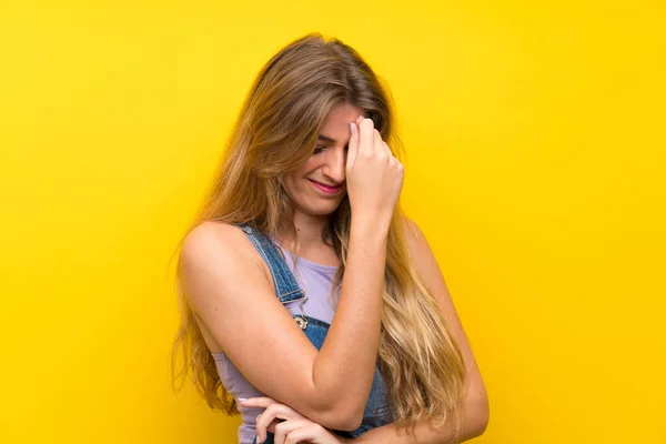 Jovem Loira Com Macacão Sobre Fundo Amarelo Isolado Rindo — Fotografia de Stock