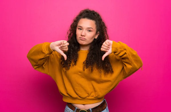 Adolescente Chica Sobre Rosa Pared Mostrando Pulgar Hacia Abajo —  Fotos de Stock