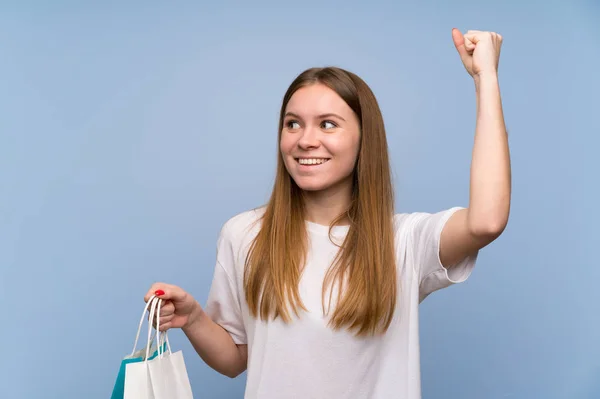 Young Woman Blue Wall Holding Lot Shopping Bags Victory Position — Stock Photo, Image