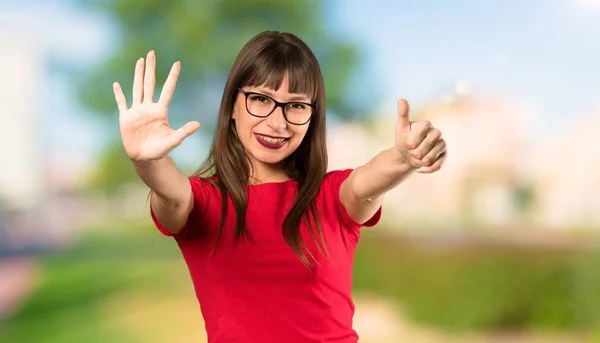 Woman with glasses counting six with fingers at outdoors