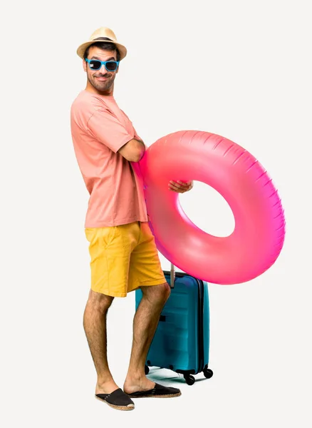 Full body of Man with hat and sunglasses on his summer vacation keeping the arms crossed in lateral position while smiling. Confident expression on isolated background