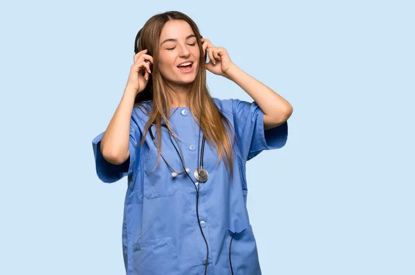 Jonge Verpleegster Luisteren Naar Muziek Met Hoofdtelefoon Geïsoleerde Blauwe Achtergrond — Stockfoto
