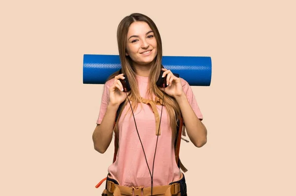 年轻的背包客女人 带着独立黄色背景的耳机 — 图库照片
