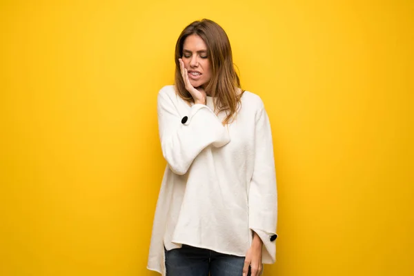 Blonde woman over yellow wall with toothache