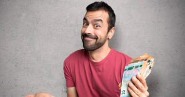 Dokulu duvarın üzerinde el ve omuz kaldırırken şüphelerle çok para alan adam