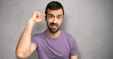 Dokulu duvarın üzerinde kafasına parmak koyarak delilik jesti yapan yakışıklı adam