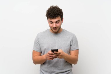 Cep telefonu kullanarak izole duvar üzerinde kıvırcık saçlı adam