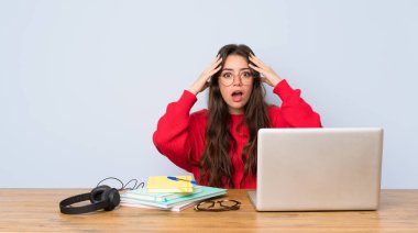 Genç öğrenci kız sürpriz ifade ile bir masada okuyan