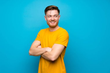 Kolları çapraz ve mutlu mavi duvar üzerinde Redhead adam