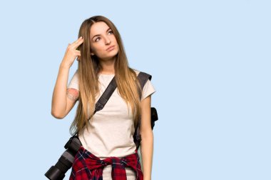 İzole edilmiş mavi arka planda intihar jesti yapan genç fotoğrafçı kadın.