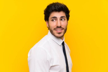 İzole sarı arka plan üzerinde Işadamı ayakta ve yan bakıyor