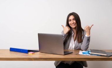 İş kadını bir ofiste jest kadar bir başparmak veren ve gülümseyerek