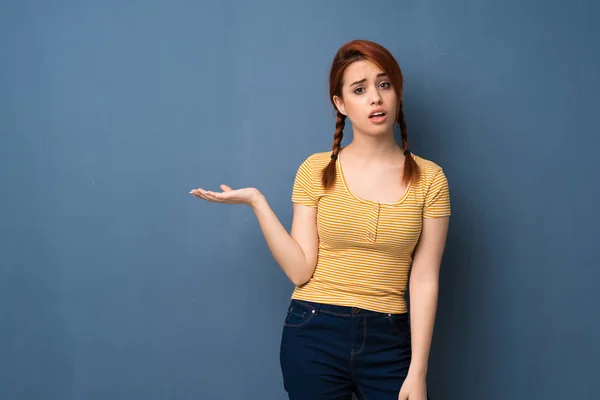 Jovem Ruiva Mulher Sobre Fundo Azul Sério Enquanto Segurando Copyspace — Fotografia de Stock