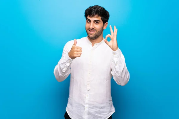 Joven Hombre Sobre Aislada Pared Azul Mostrando Signo Con Dando —  Fotos de Stock