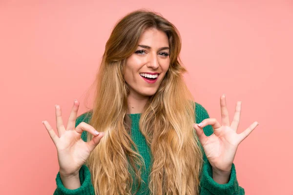 Junge Blonde Frau Mit Grünem Pullover Über Rosa Wand Zeigt — Stockfoto