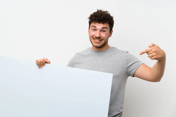 コンセプトを挿入するための空の白いプラカードを持つ孤立した壁の上に巻き毛を持つ男 — ストック写真
